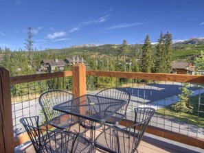 Ein Balkon mit Metalltisch und -stühlen mit Blick auf eine Berglandschaft und einen Pool.