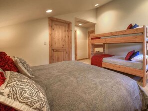 A bedroom with a large bed, a bunk bed, and a wooden door.