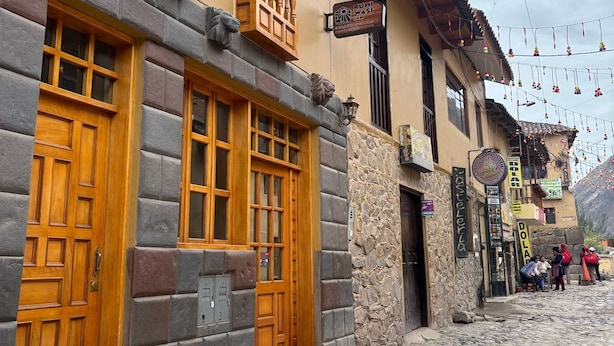 Un bâtiment traditionnel avec des portes et des fenêtres en bois, une façade en pierre et une enseigne indiquant « Rumi Wasi Inn ».