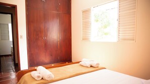 Une chambre d’hôtel avec un lit, une armoire en bois et une fenêtre avec des stores.