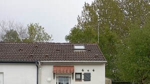 En liten, envåningsbyggnad med ett tak täckt av takpannor och en vit fasad. Den har en ytterdörr, ett litet fönster och en dörrklocka.