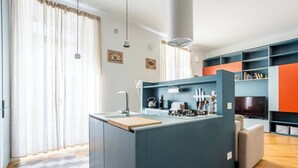Eine moderne Küche mit Kochinsel, integrierten Geräten und einer Sitzecke mit Fernseher.
