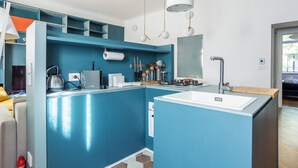 Eine moderne Küche mit blauen Schränken, einer weißen Spüle sowie verschiedenen Küchenutensilien und Geräten.