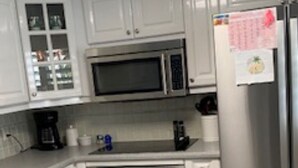 A modern kitchen with white cabinets, a stainless steel refrigerator, a microwave, an oven, and a dishwasher. - 2-bedroom condo, 5 min to private beach, golf, tiki new pool, hot tub fitness rm (Fort Pierce)