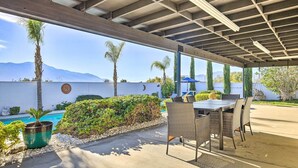 An outdoor patio with a pool, seating area, and mountain views.