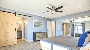 A bedroom with a bed, a dresser, a mirror, a ceiling fan, and a sliding barn door.