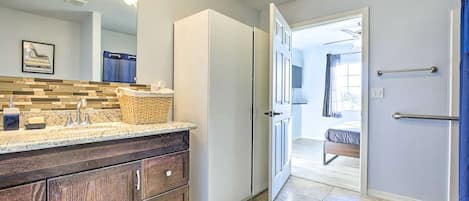 A modern bathroom with a large mirror, wooden vanity, and a wicker basket on the countertop.