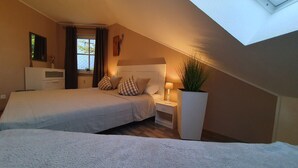 A bedroom with two beds, a nightstand, a lamp, a radiator, and a window with curtains. - Harzblick apartment - your retreat in the middle of nature (Braunlage)