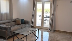 A modern living room with a sectional sofa, a glass coffee table, and a ceiling light fixture.