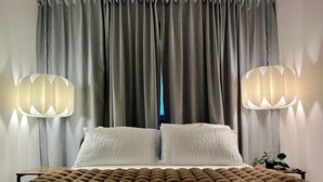 A bed with a brown blanket, two white pillows, and a nightstand with a plant. - Beautiful legal suite | Private sauna (Calgary)