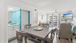 Una sala de estar moderna con comedor, televisor y vista al mar.