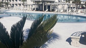 Un hotel con piscina, palmeras y un cielo azul despejado.