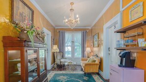 A room with a chandelier, a sofa, a table, and a cabinet.