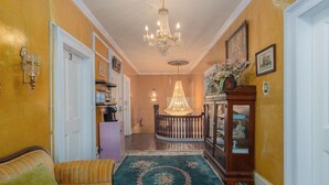 A hallway with a sofa, a chandelier, a decorative rug, and a cabinet with glass doors.
