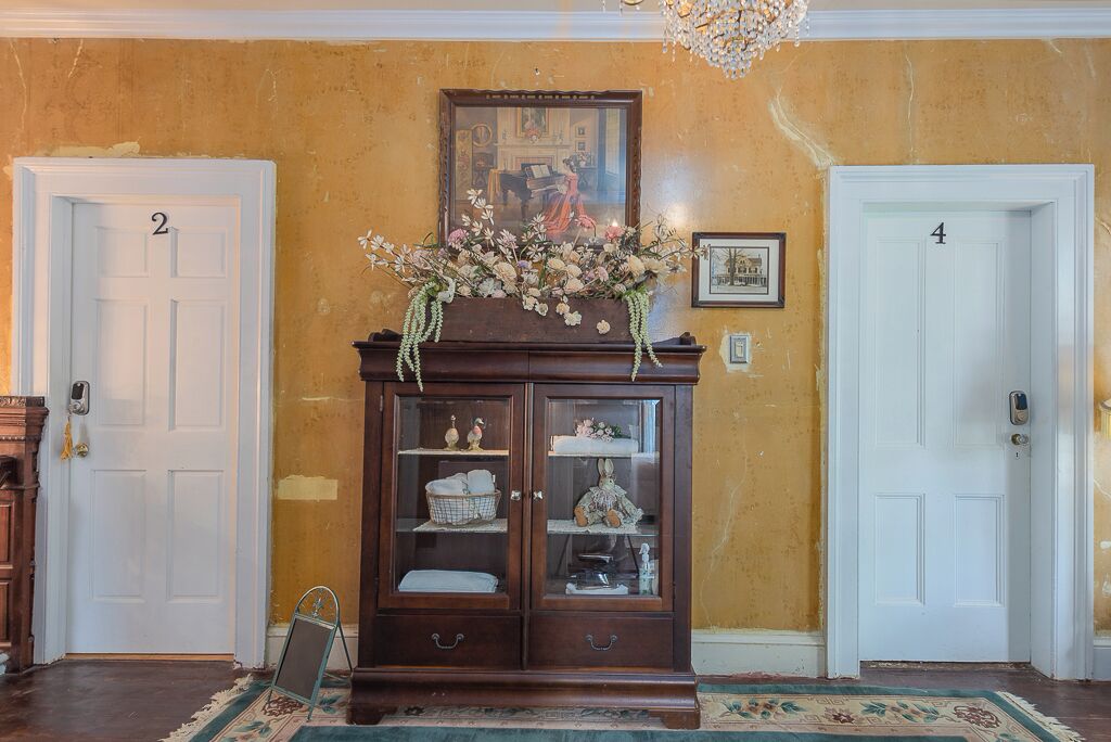 A hallway with a wooden cabinet, two white doors labeled 2 and 4, and a chandelier.