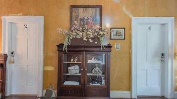 A hallway with a wooden cabinet, two white doors labeled 2 and 4, and a chandelier.