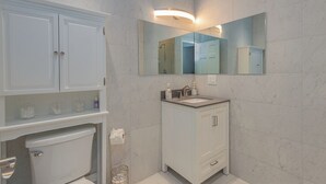 A bathroom with a toilet, sink, and cabinets.
