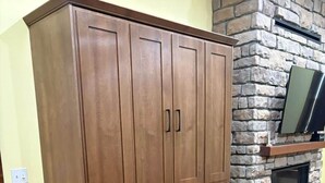 Un escritorio de madera con una silla, una chimenea de piedra y un televisor montado en la pared.