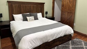 Una cama bien hecha con cabecera de madera, una manta gris y un cojín con la inscripción 'Sweet Dreams'.