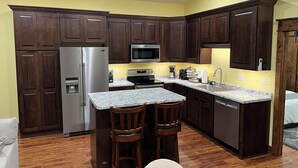 Una cocina con armarios de madera oscura, electrodomésticos de acero inoxidable, encimera de granito y microondas integrado.