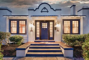 Ein zweigeschossiges Haus mit einer blauen Tür, Hausnummer 610, und einem kleinen Vorbau mit Stufen zum Eingang.