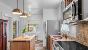 Una cocina moderna con una isla de madera, electrodomésticos de acero inoxidable e iluminación colgante.