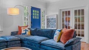 Una sala de estar con un sofá seccional azul, una lámpara y una puerta azul.