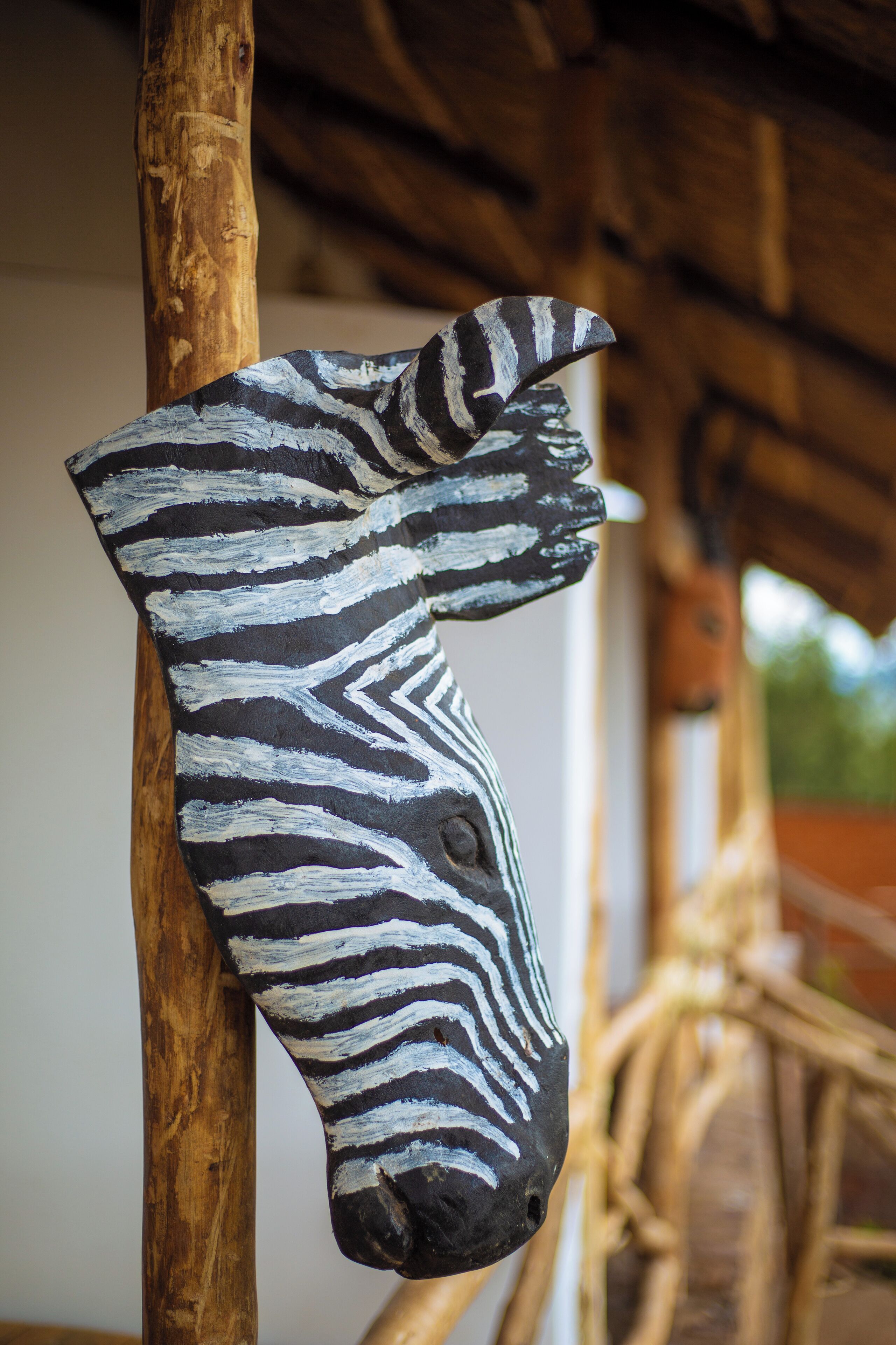 A zebra head sculpture mounted on a wooden post.