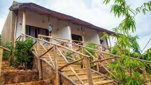 A rustic building with a stone staircase and wooden railings. - Akagera Park Inn (Rwinkwavu)