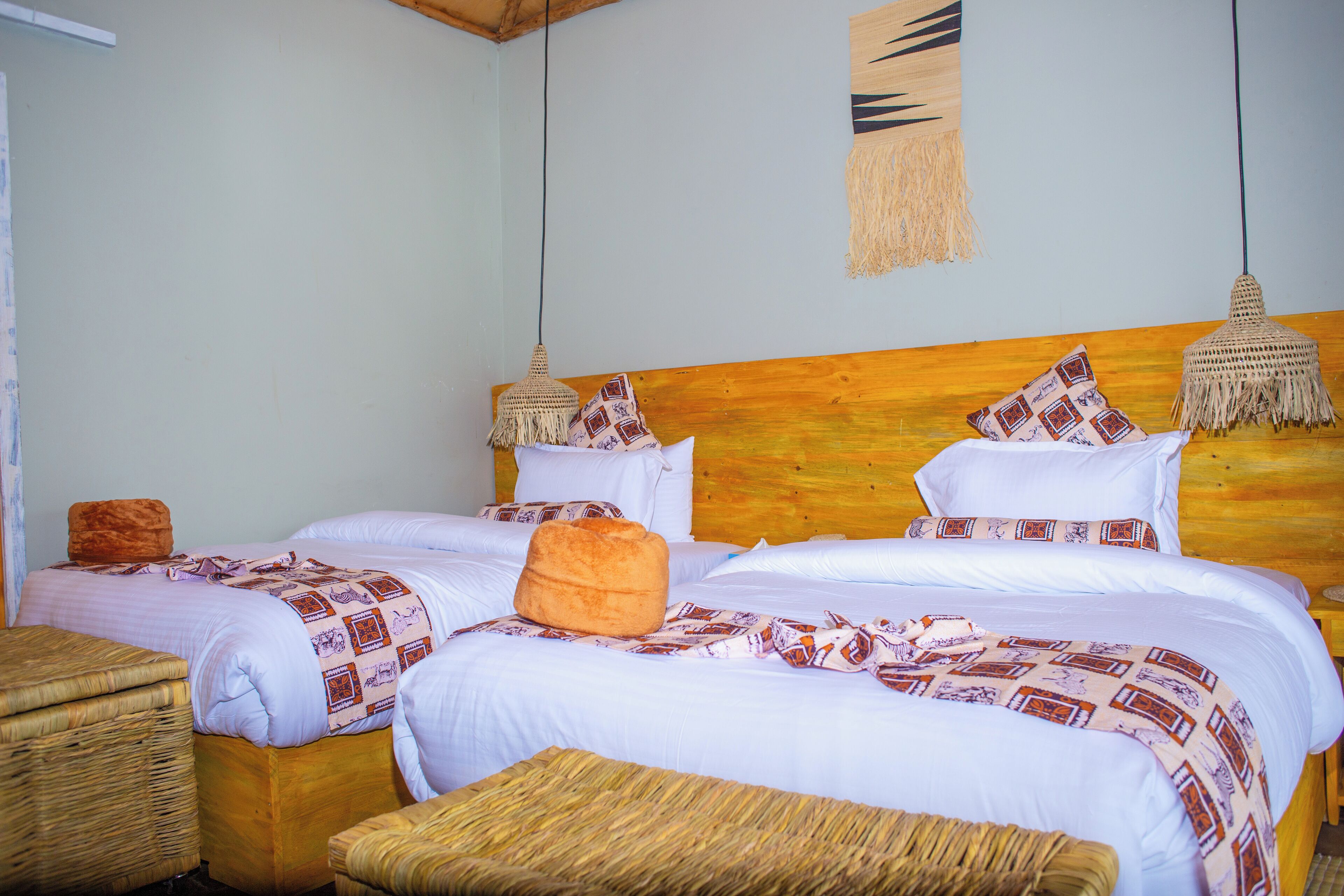 A double bed with white linens and patterned blankets, a wooden headboard, and two hanging lamps.