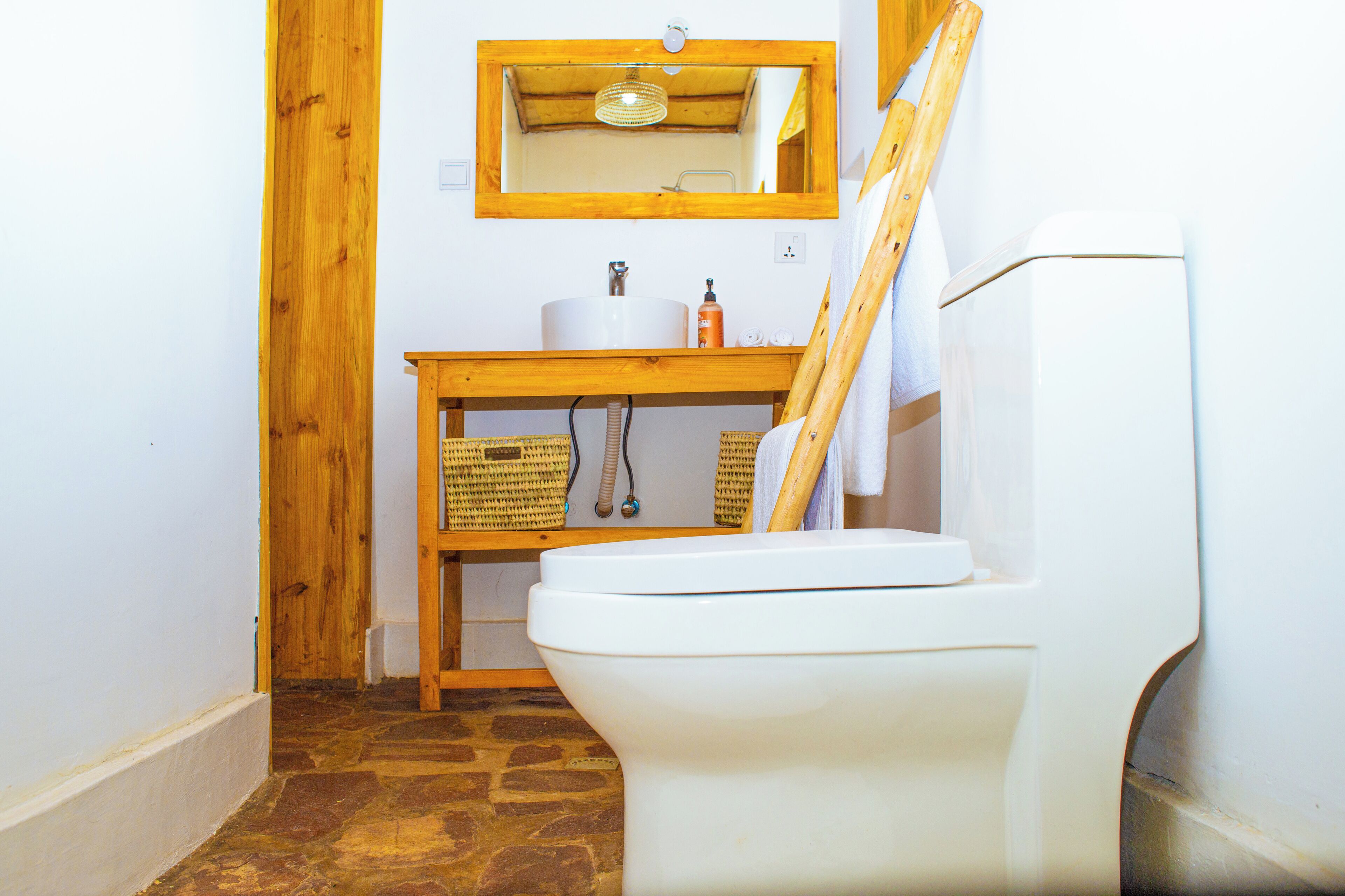 A bathroom with a white toilet, wooden vanity, and a mirror above the sink.