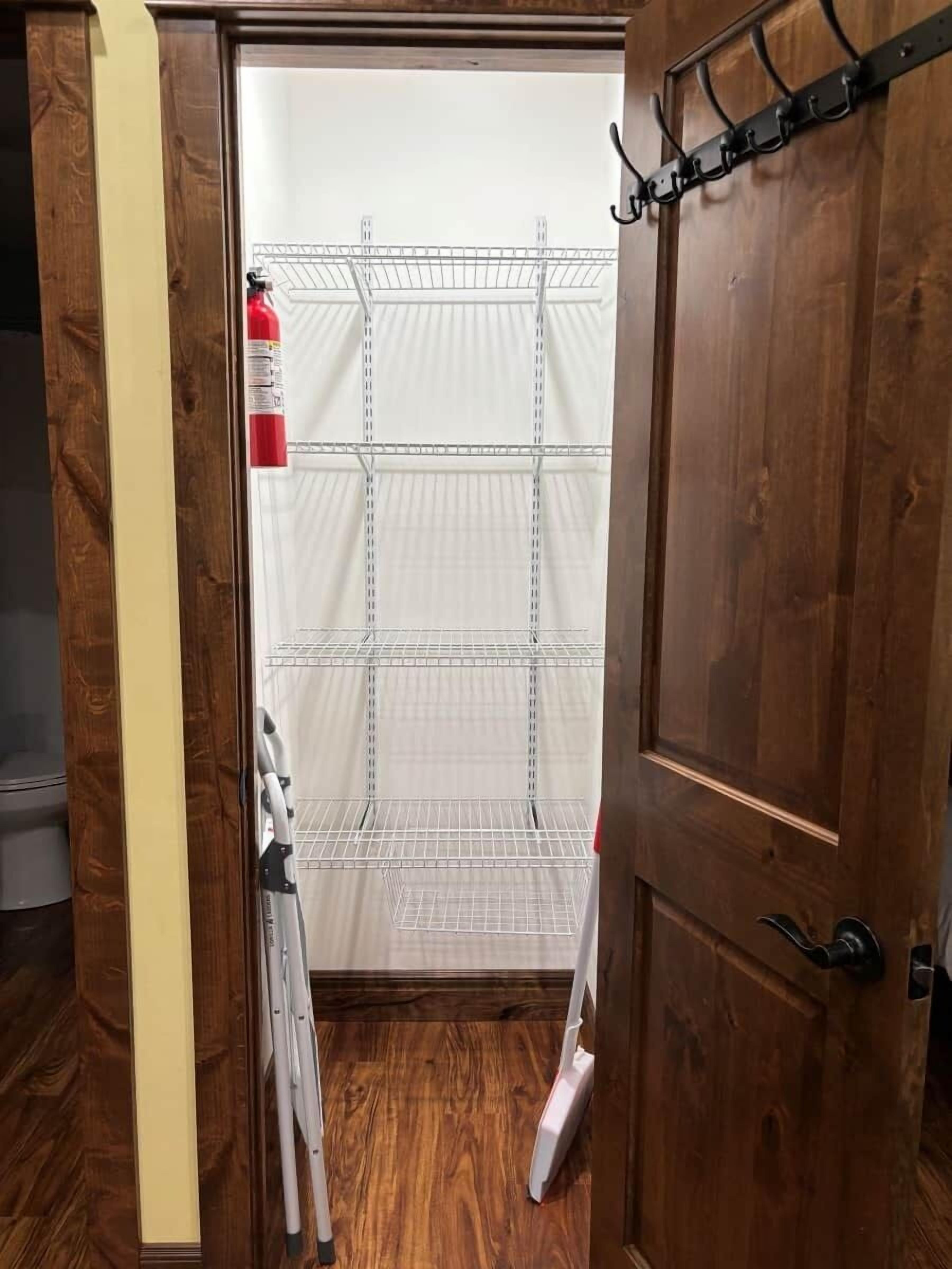 A wooden door with a metal shelf unit and a fire extinguisher on the wall.