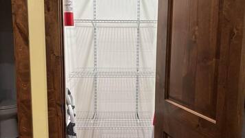 A wooden door with a metal shelf unit and a fire extinguisher on the wall.