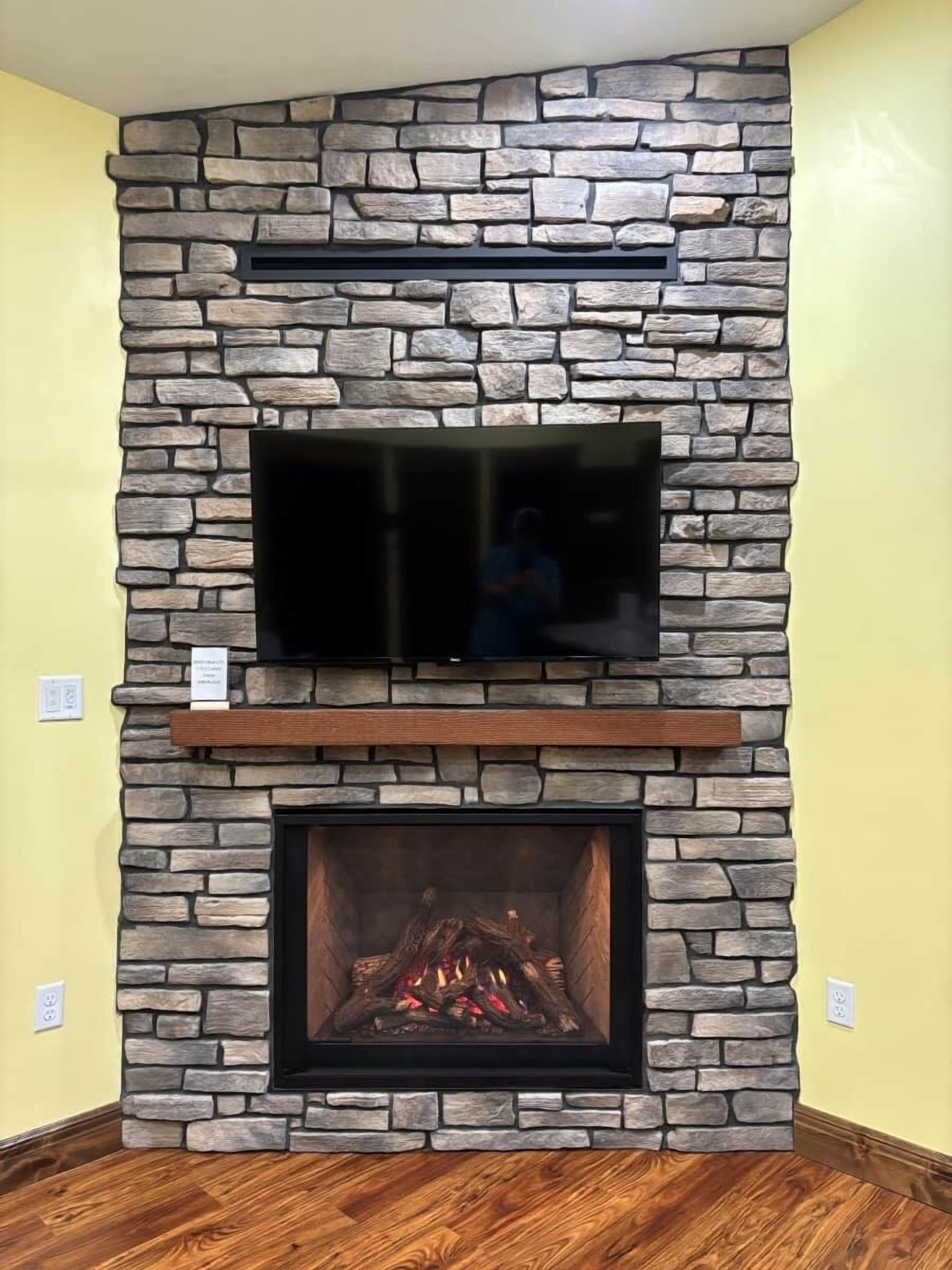 A stone fireplace with a TV mounted above it and a fire burning inside.