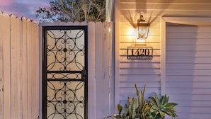 A gated entrance with a decorative metal gate, a mailbox with the address "1420 Bluebird Lane", and a wall-mounted light fixture. - Ocean-View Retreat • Walk to La Jolla Cove & Village • Full Kitchen • Modern 1BR (La Jolla)