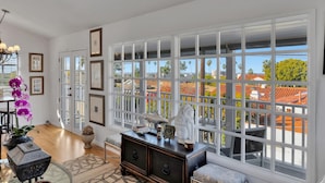 A spacious room with large windows, a wooden floor, and a view of a residential area. - Ocean-View Retreat • Walk to La Jolla Cove & Village • Full Kitchen • Modern 1BR (La Jolla)