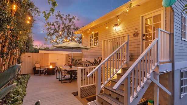 A wooden deck with outdoor furniture, a covered seating area, and a staircase leading to a house. - Ocean-View Retreat • Walk to La Jolla Cove & Village • Full Kitchen • Modern 1BR (La Jolla)