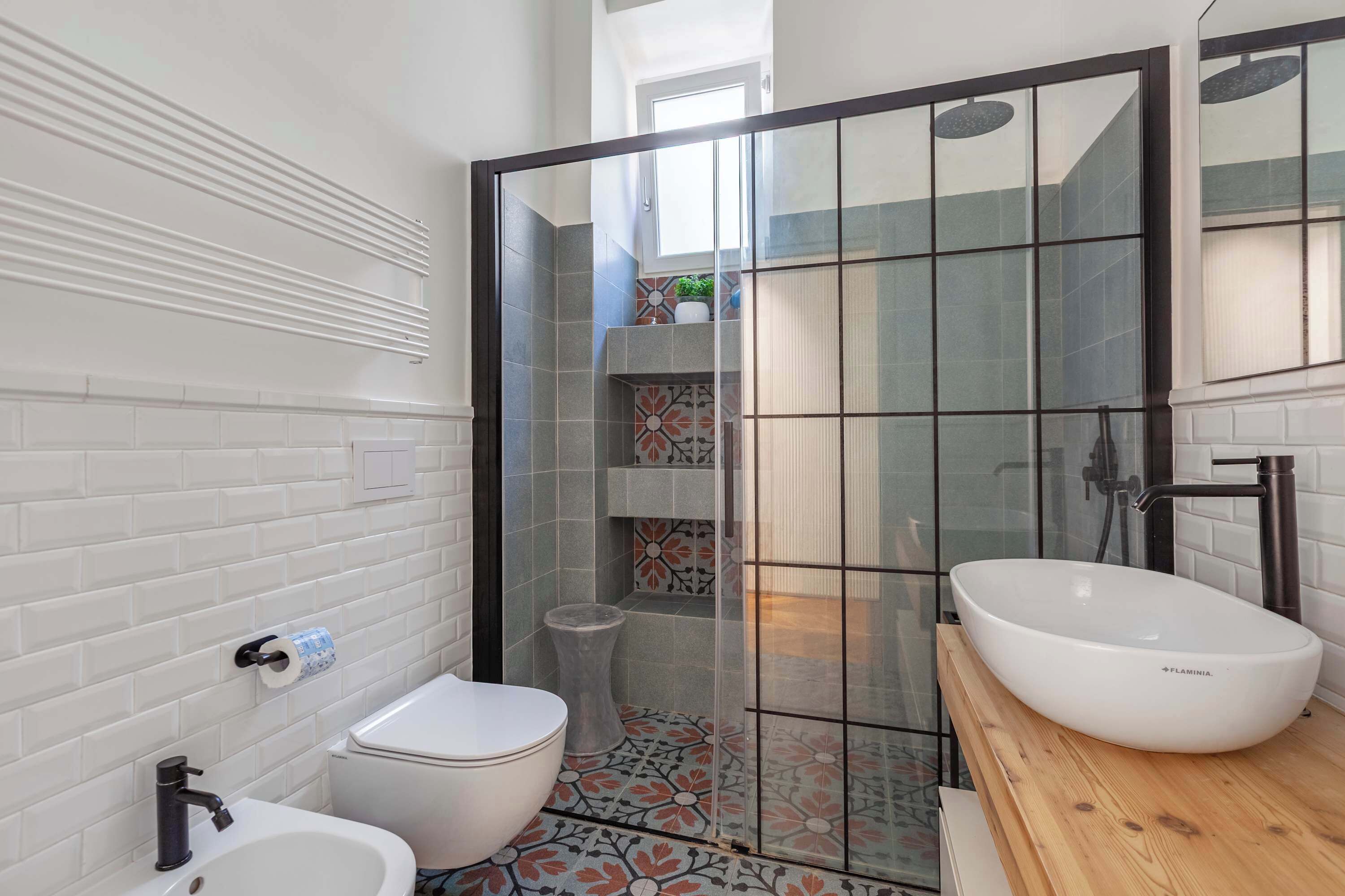Een moderne badkamer met een wit toilet, een bidet en een grote witte wastafel.