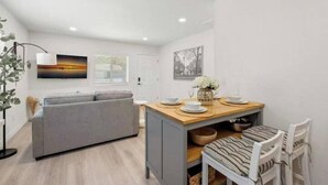 Un espacio habitable compacto con sofá, una mesa de comedor y una pequeña cocina.