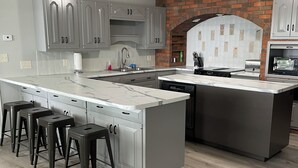 Una cocina moderna con una isla grande, armarios grises y una pared de ladrillo decorativa.