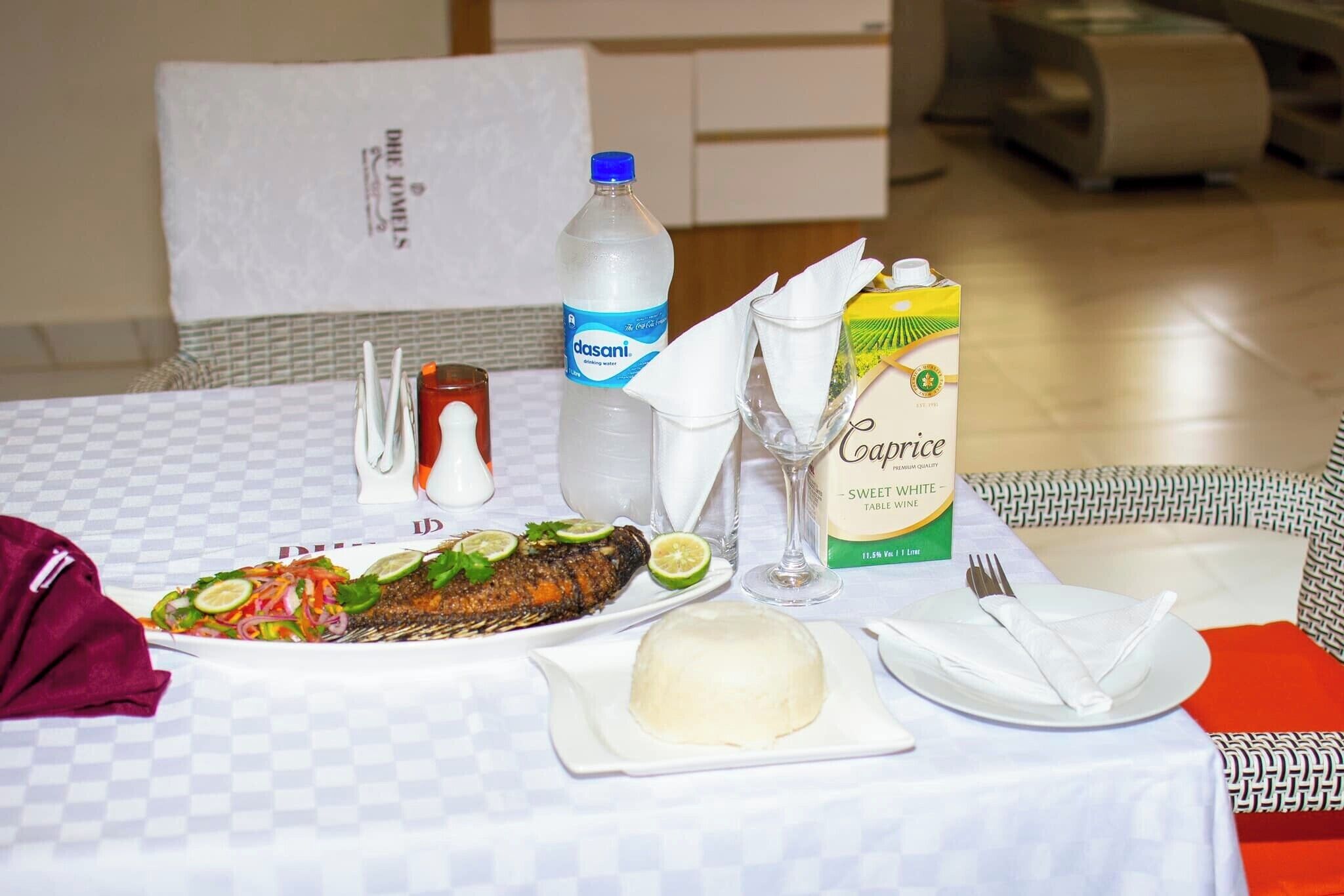Una tavola imbandita con un pasto, che include un piatto di pesce, una bevanda e un succo di frutta in cartone.