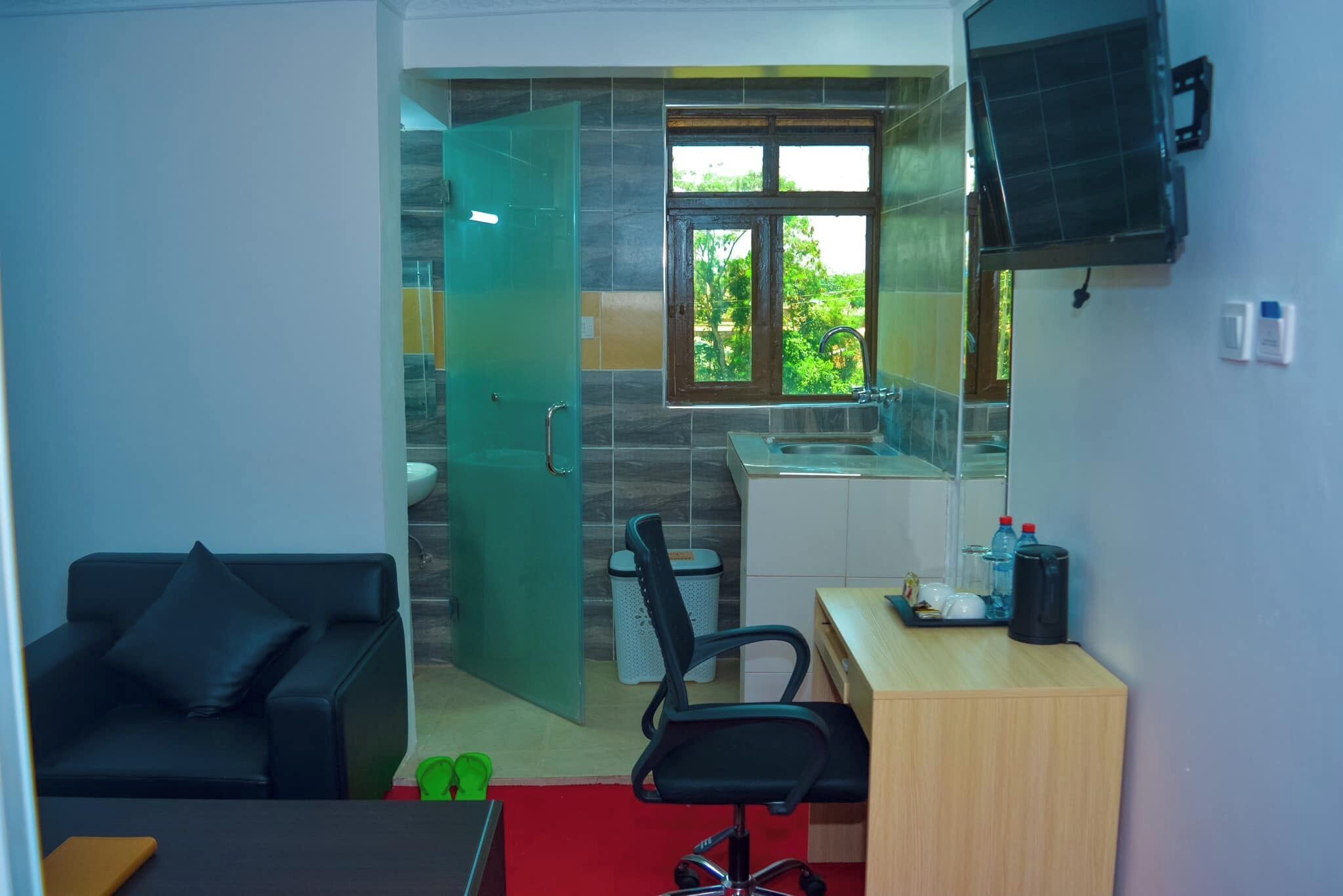 Habitación compacta con sofá, escritorio, silla, kitchenette y baño.