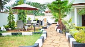 Un patio con mobiliario exterior, un letrero de zona para fumadores y un sendero bordeado por macetas.