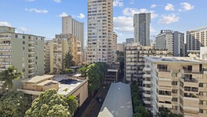 Un edificio residencial alto con varios balcones, rodeado de otros edificios y áreas verdes.