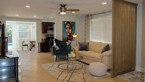 A modern living room with a sofa, armchair, coffee table, and a painting on the wall. - Beautifully Remodeled Home with Pool Near Siesta (Sarasota)