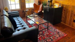 A cozy living room with a leather sofa, a glass coffee table, and a red patterned rug. - Hubbard Shores (Breckenridge)