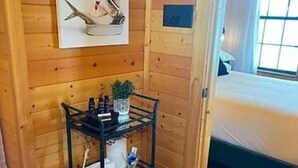 A wooden cabin room with a bunk bed, a small shelf with toiletries, and a framed picture on the wall. - Hubbard Shores (Breckenridge)