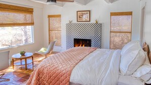A bedroom with a bed, a fireplace, a ceiling fan, and a window with a view of trees. - Luxury Home on 100 acre Secluded Ranch, Waterfront, Little Frio Creek (Leakey)