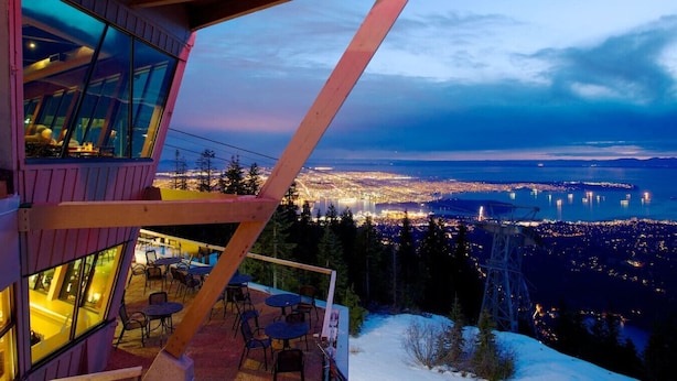 A modern building with large windows overlooking a cityscape at dusk. - Luxury Scandinavian Suite| Cozy and Bright (North Vancouver)