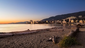 A beach with a cityscape in the background, featuring a mix of natural and urban elements. - Luxury Scandinavian Suite| Cozy and Bright (North Vancouver)